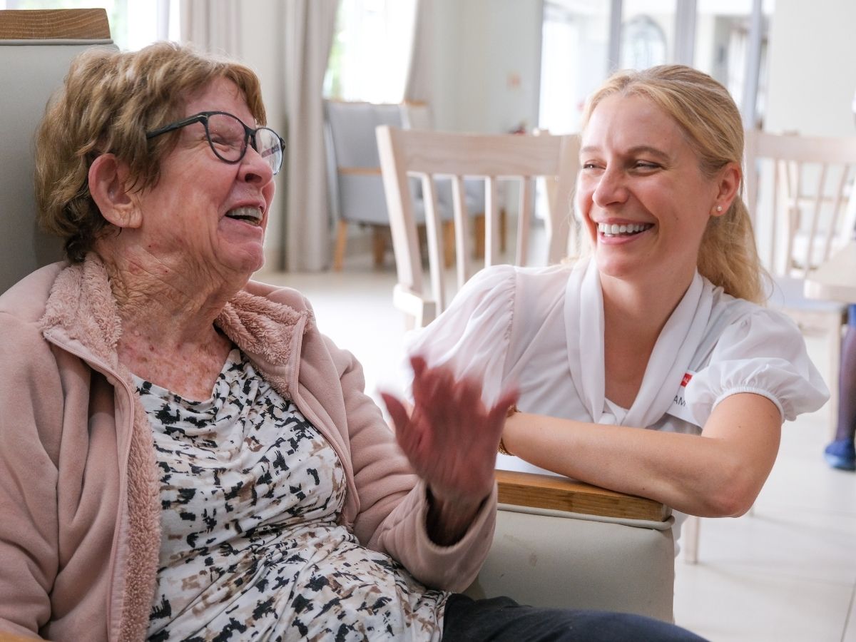 An older woman and a care team member sharing a warm moment
