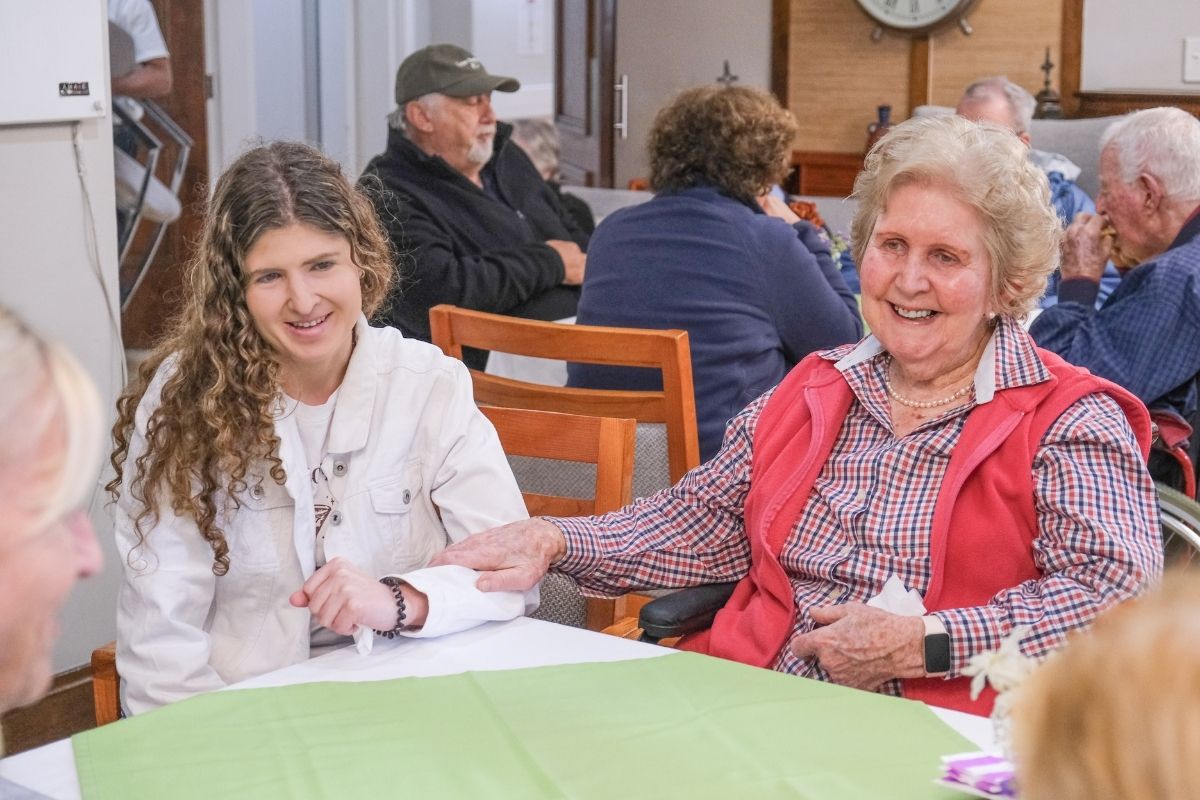 An older woman enjoying company around a table