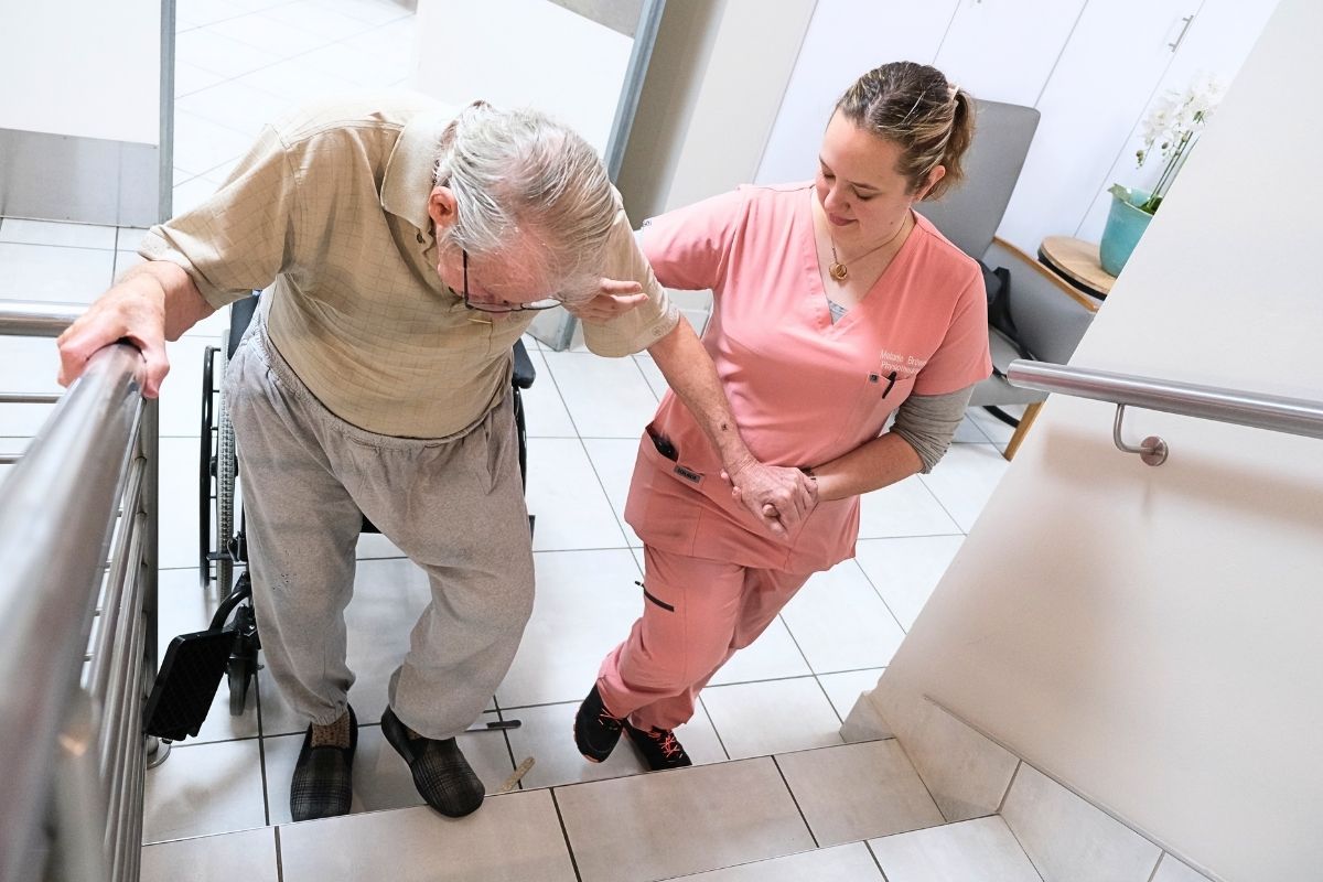 An older man receiving assistance with mobility