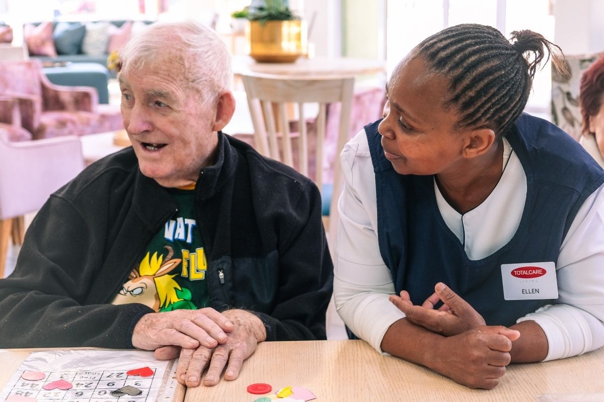 A TOTALCARE carer supporting a resident during a table activity